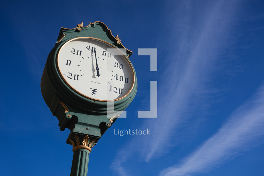 Old fashioned thermometer against blue sky