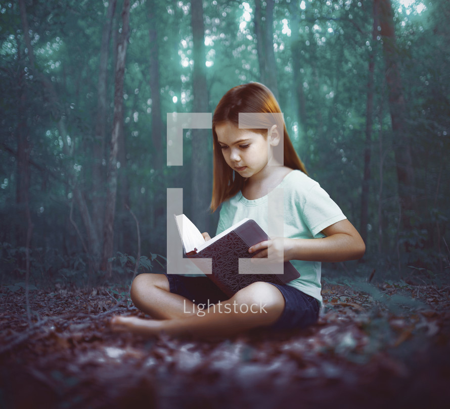 A young girl reads alone in the dark forest
