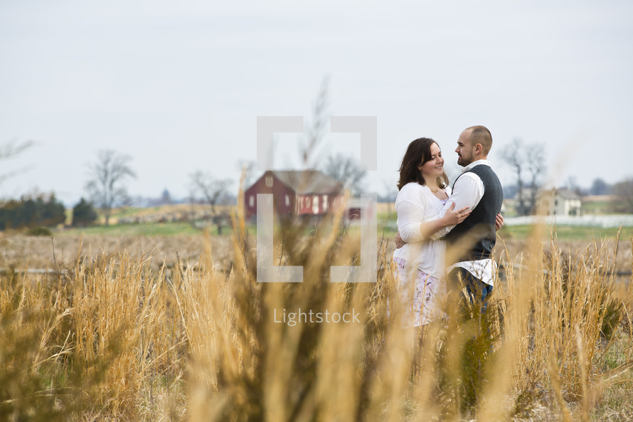 couple standing in a field hugging 