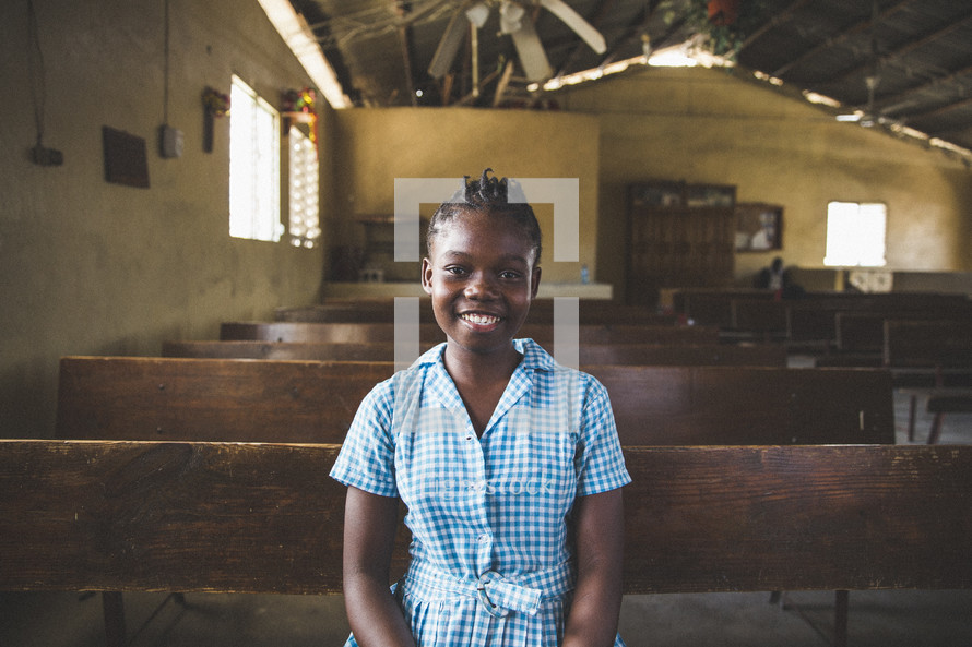 Smiling girl sitting in a church pew.