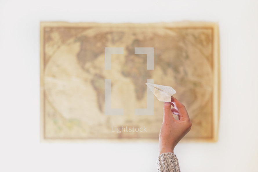 a woman throwing a paper airplane at a world map 