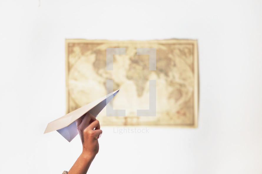 a woman throwing a paper airplane and a map on a wall 