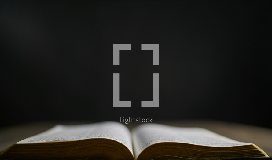 Open bible on a table with dark background