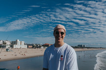a man in a beanie standing on a beach 