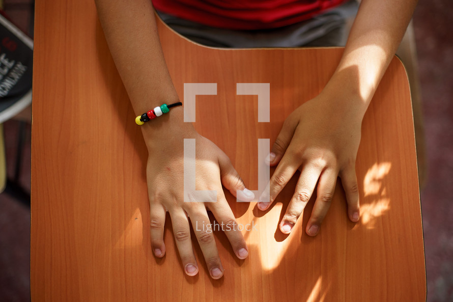 overhead view of a child's hands on a desk 