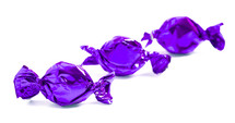 three purple wrapped candies on a white background 