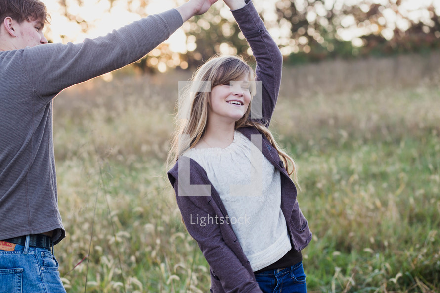 a young couple dancing in a field of tall grass in fall 