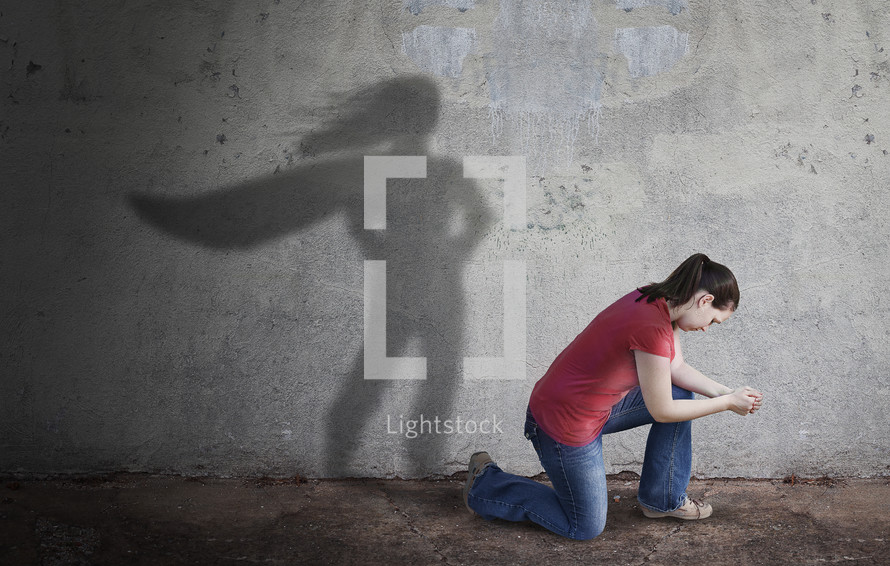 a woman praying and a shadow of a superhero 
