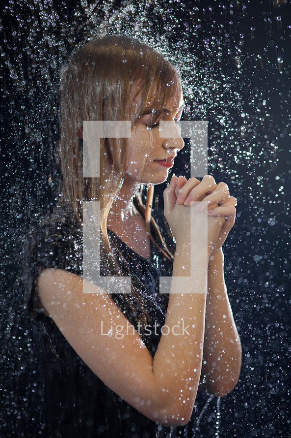 a woman praying under falling rain