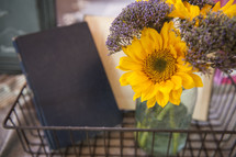 sunflowers in a vase and book in a wire basket 