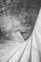Going down a spiral staircase with brick walls.