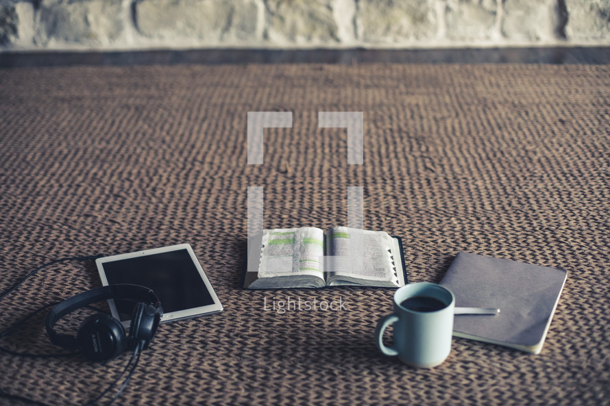 headphones, tablet, open Bible, pen, journal, and coffee cup 