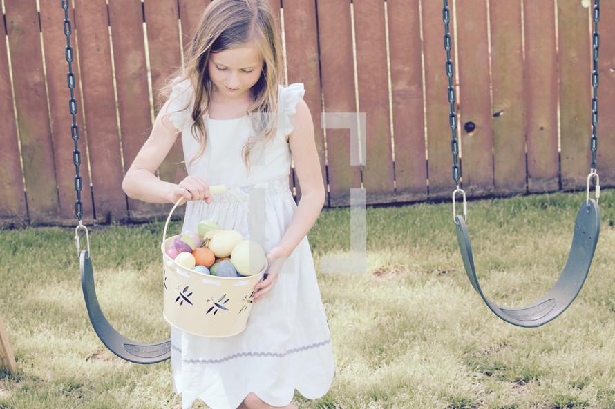 A little girl searching for eggs in a backyard Easter egg hunt 