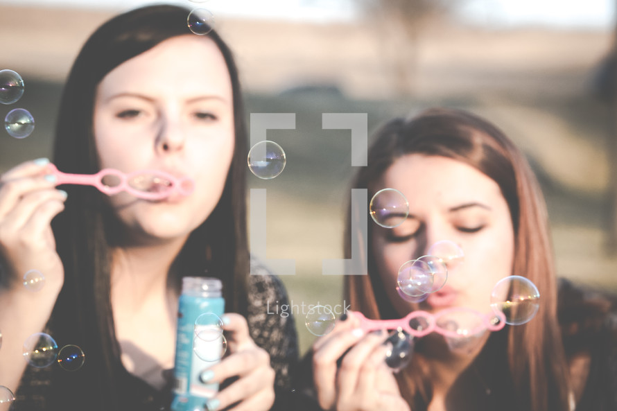 Two girls blowing bubbles.