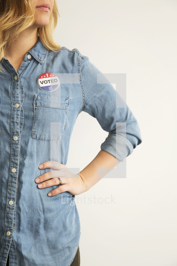 A woman wearing a denim shirt and an "I Voted," button.