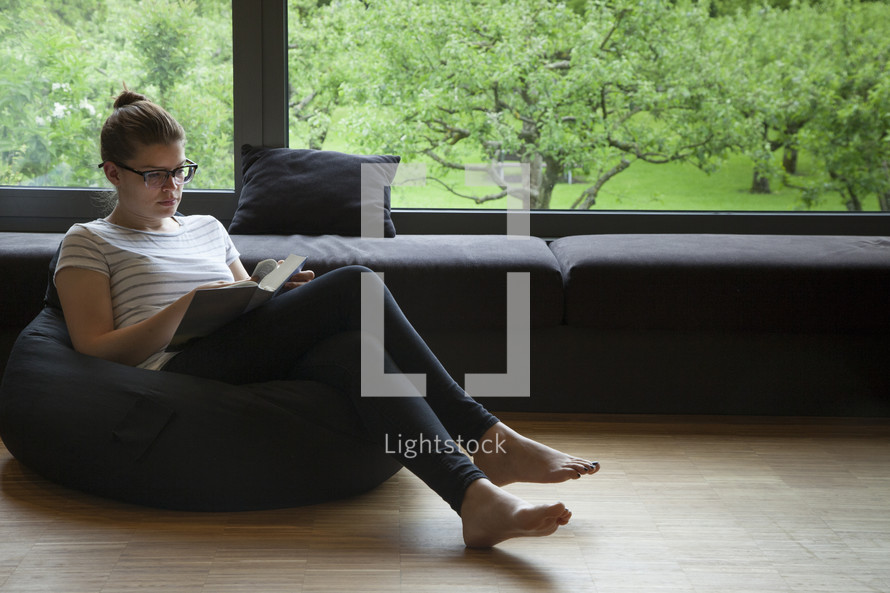 a woman sitting in a beanbag reading a Bible 