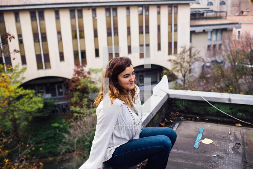 young woman sitting on the edge of a roof 