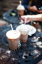 Iced coffee drinks in plastic cups on table at an outdoor bistro cafe.