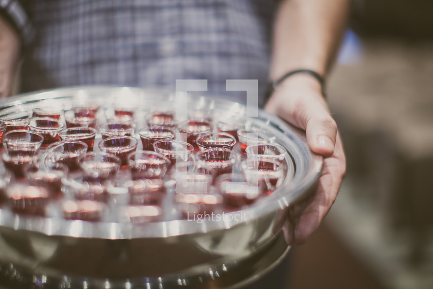 man holding a tray of communion cups 
