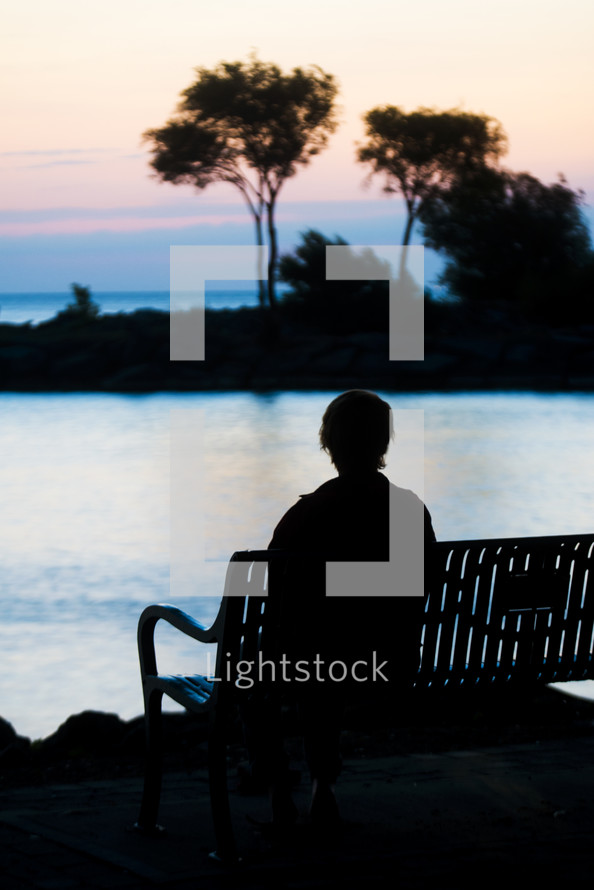 a silhouette of a boy and a bench 