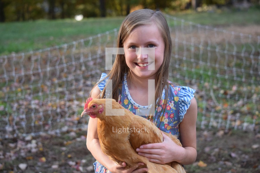 a little girl holding a chicken 