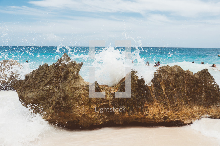 waves crashing into a rock on a beach 