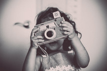 a child holding a vintage flash camera 