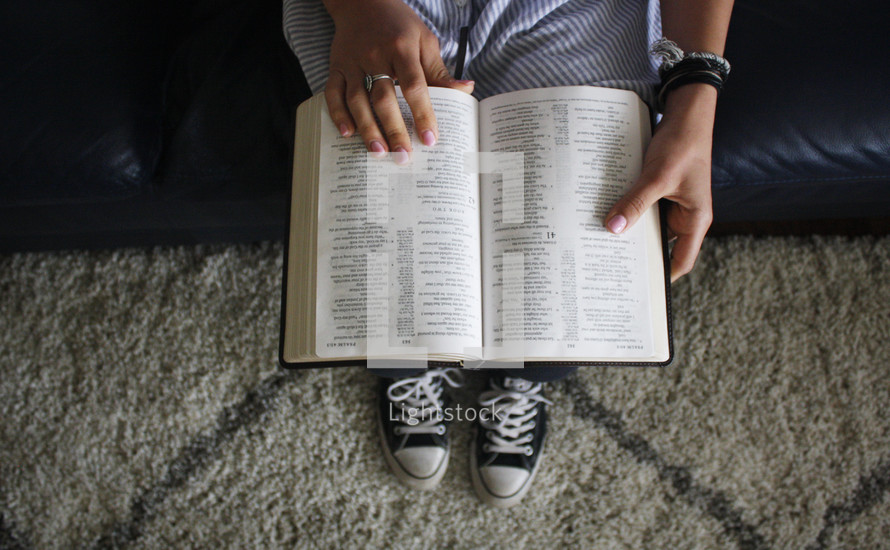 teen girl sitting on a couch reading a Bible 