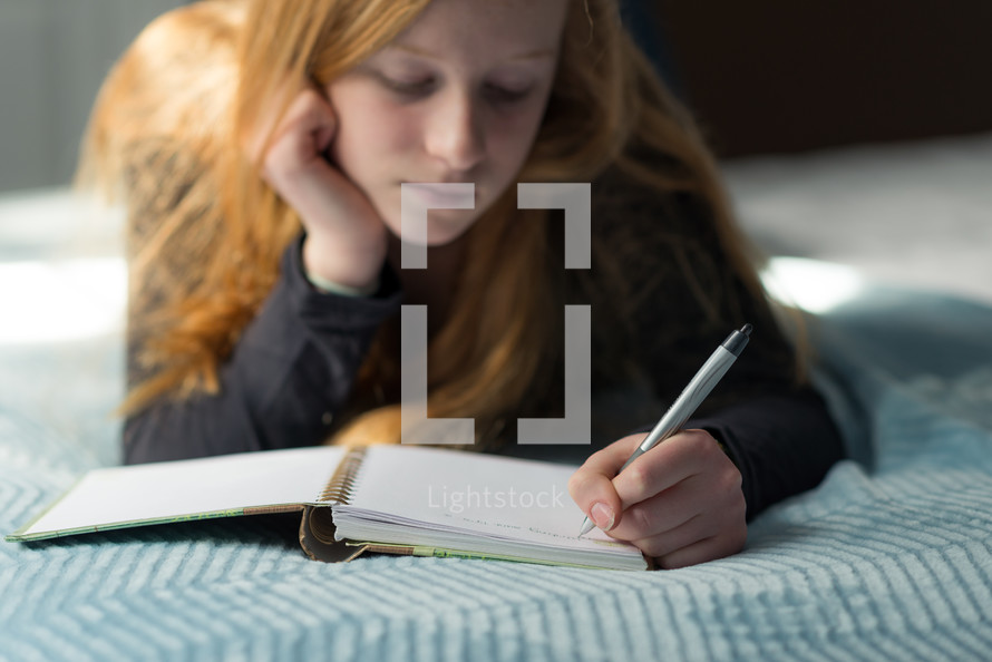 a teen girl writing in a journal 