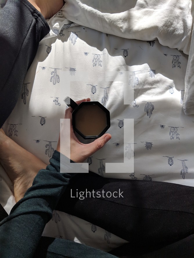 a woman sitting in a bed with a cup of coffee 