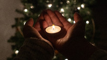 votive candle in cupped hands 