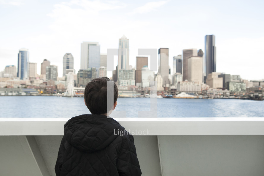a boy on a ferry watching Seattle 
