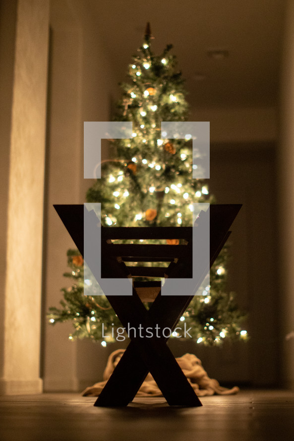 silhouette of a manger in front of a Christmas tree 