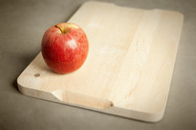red apple on a wood cutting board 