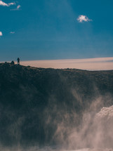 a person standing at the top of a cliff looking down at mist from a waterfall 