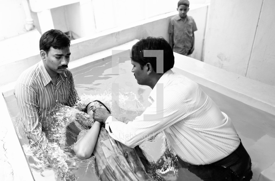 woman being dunked in water during a baptism in India
