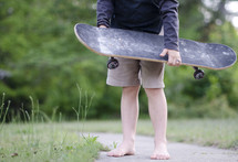 teenage boy holding a skateboard