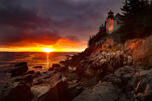 lighthouse on a rocky shore at sunset 