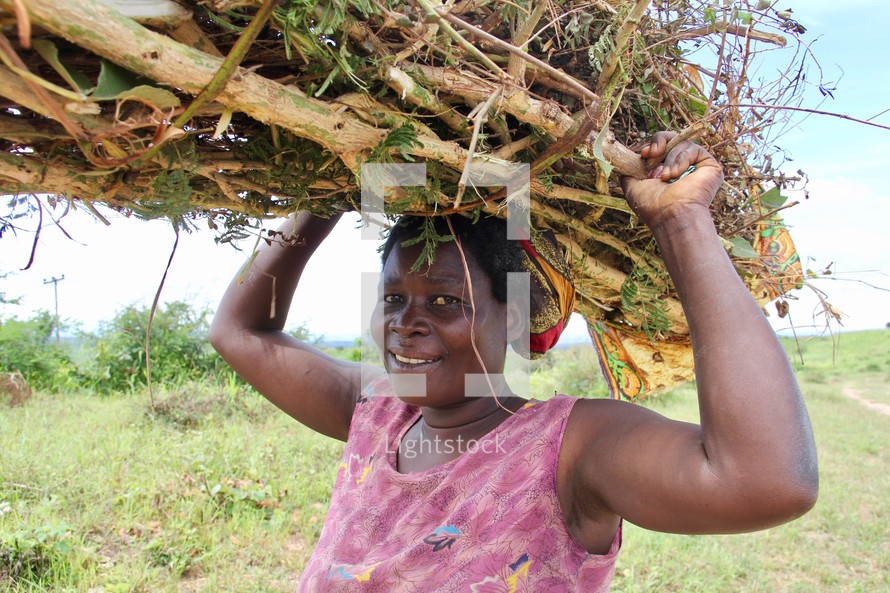 a woman carrying a bundle of sticks on her head 
