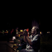 A man playing a trumpet on the street at night 