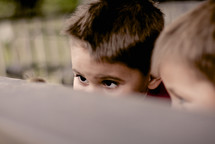 two little boys peeking over a railing 