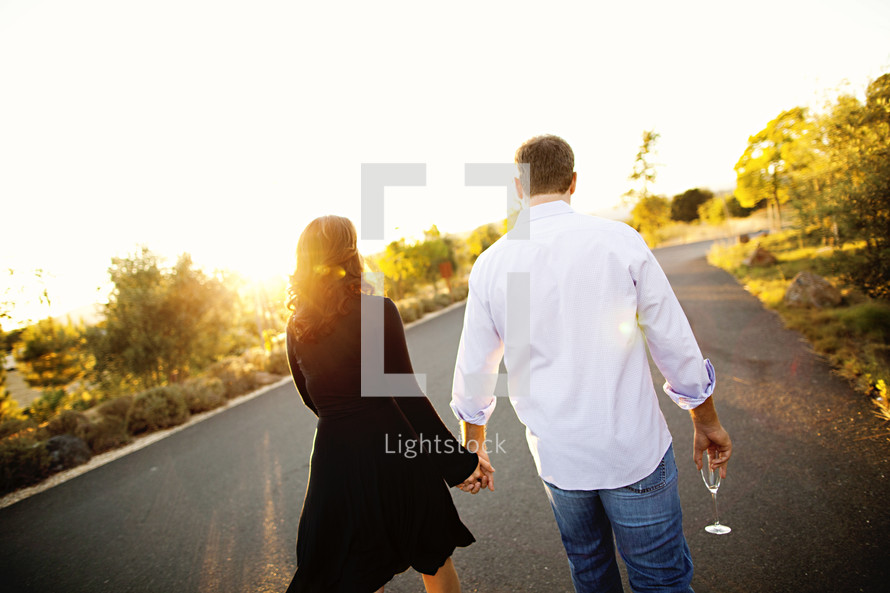 Couple holding hands walking at sunset romance wine glass in hand relationship