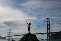 person standing with outstretched arms and Golden Gate Bridge in the background 
