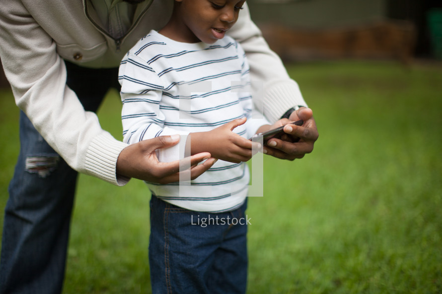 father and son looking at a cellphone screen 