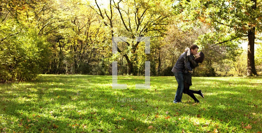 Husband and wife kissing in open grass field