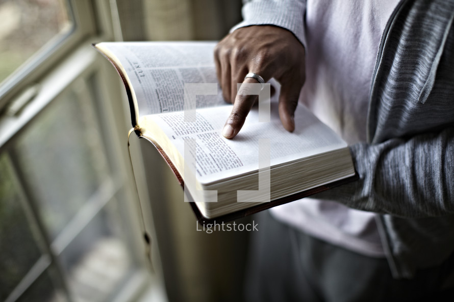 An African American man points to the last sentence in the book of "Mark" in the BIble.