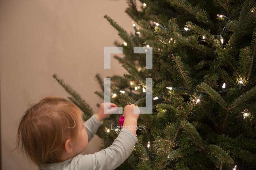 Small child hanging ornaments on a Christmas tree