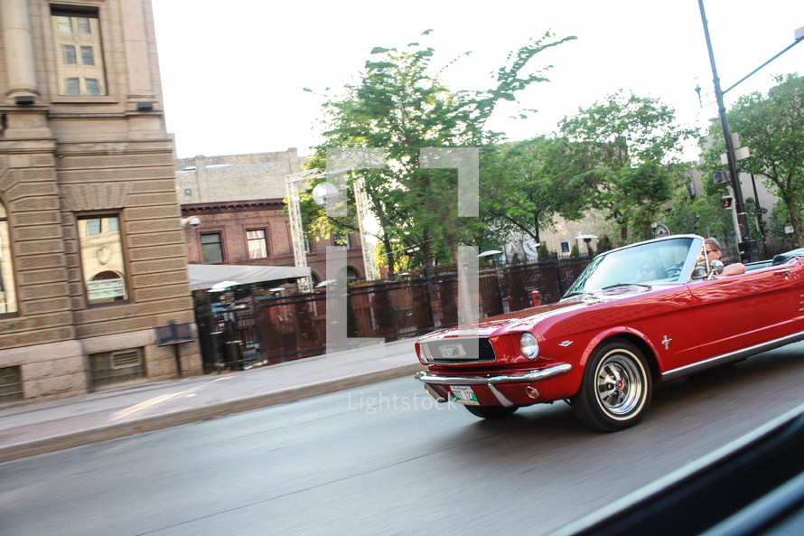 Man driving a classic mustang down the street