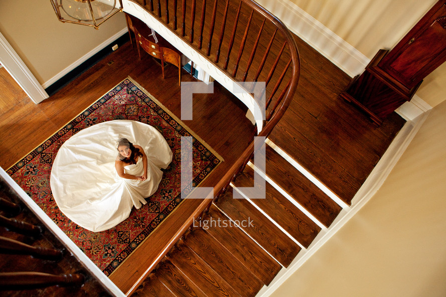 A bride in her wedding dress looking up the stairs