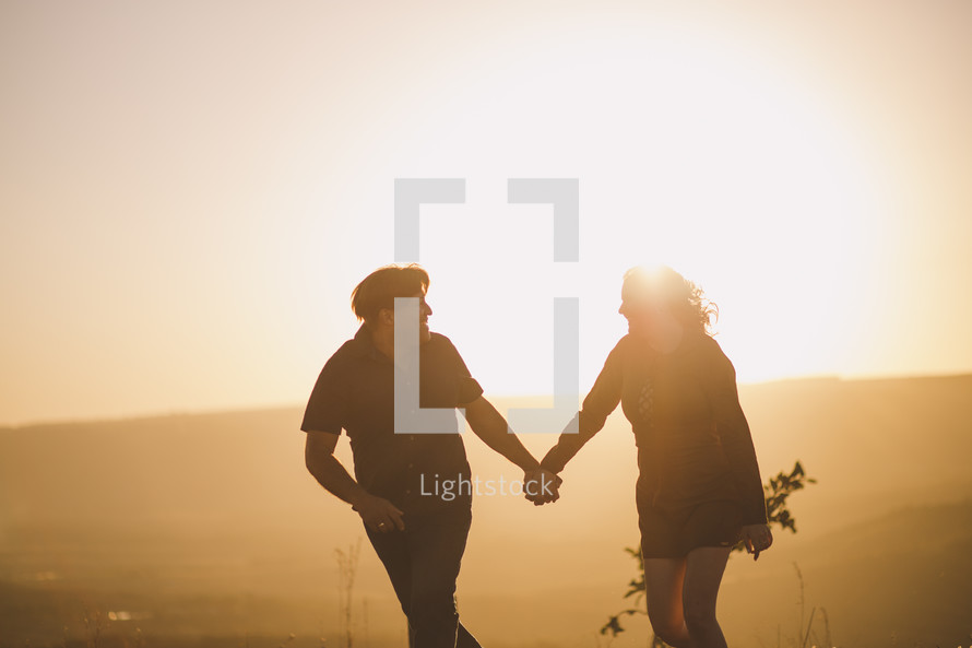 a couple walking holding hands at sunset 